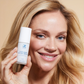 Frau hält den Pumpspender der Anti-Aging Super Cream neben ihr Gesicht